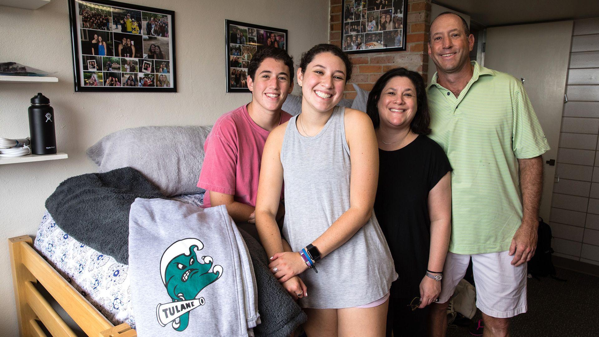 A student and his parents pose in his room on Move-In Day
